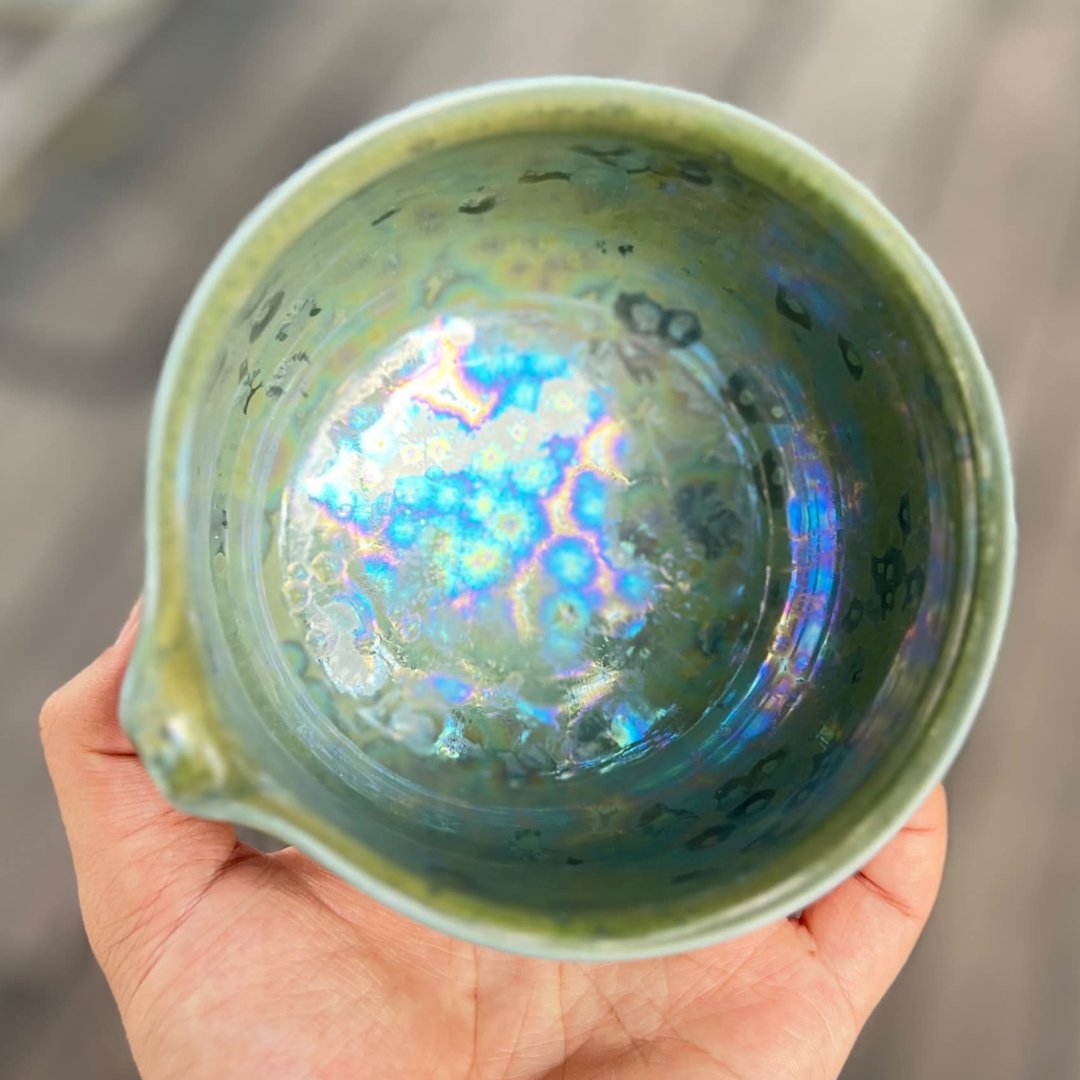 A crystal tea bowl held in the hand