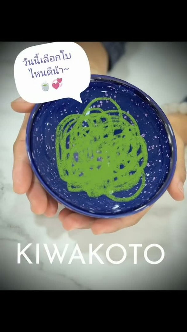 A blue tea bowl with matcha, held in the hand
